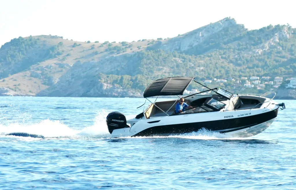 Motorboot mit Sonnendach vor der felsigen Küste