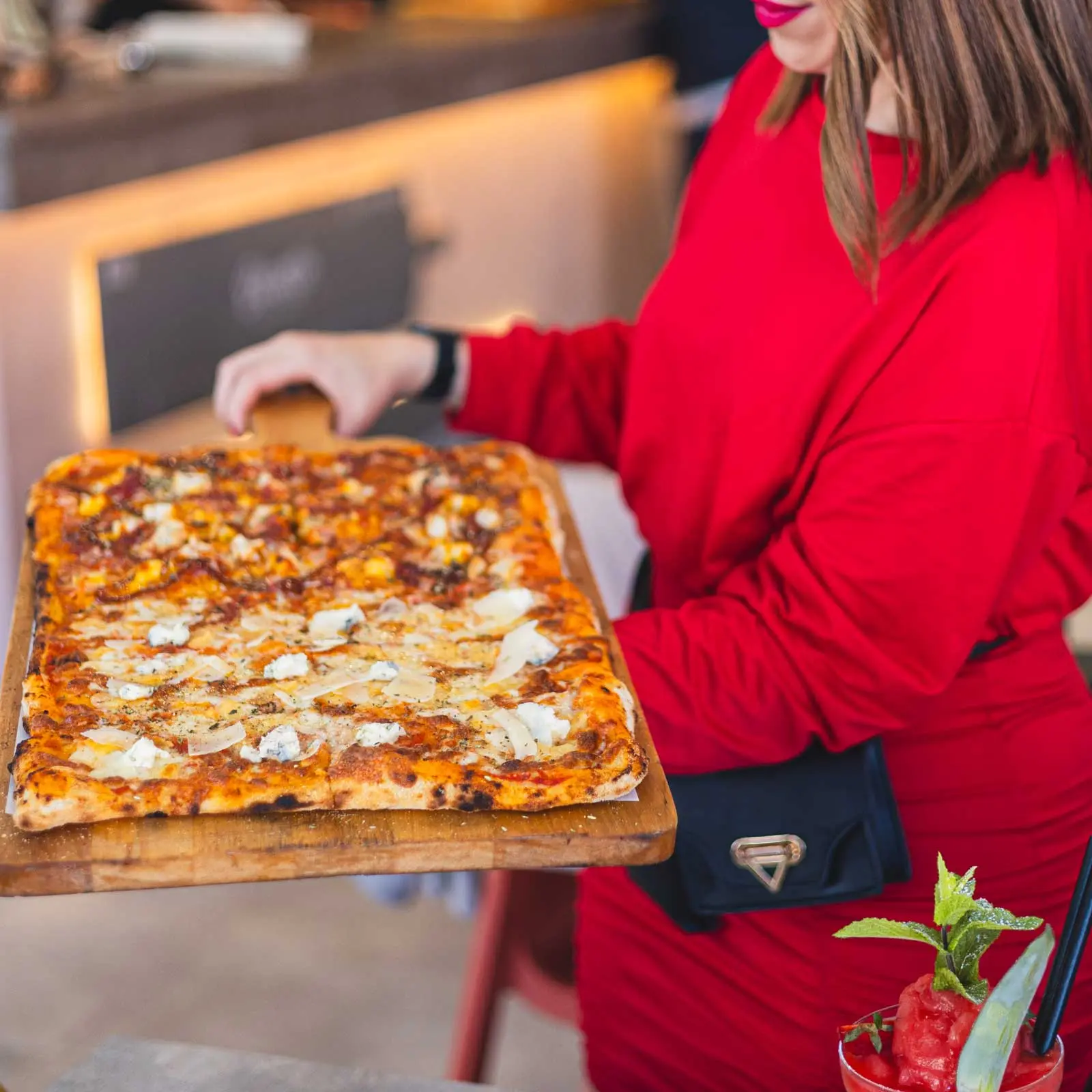 Guest in red serving pizza by the metre at ENCANTO
