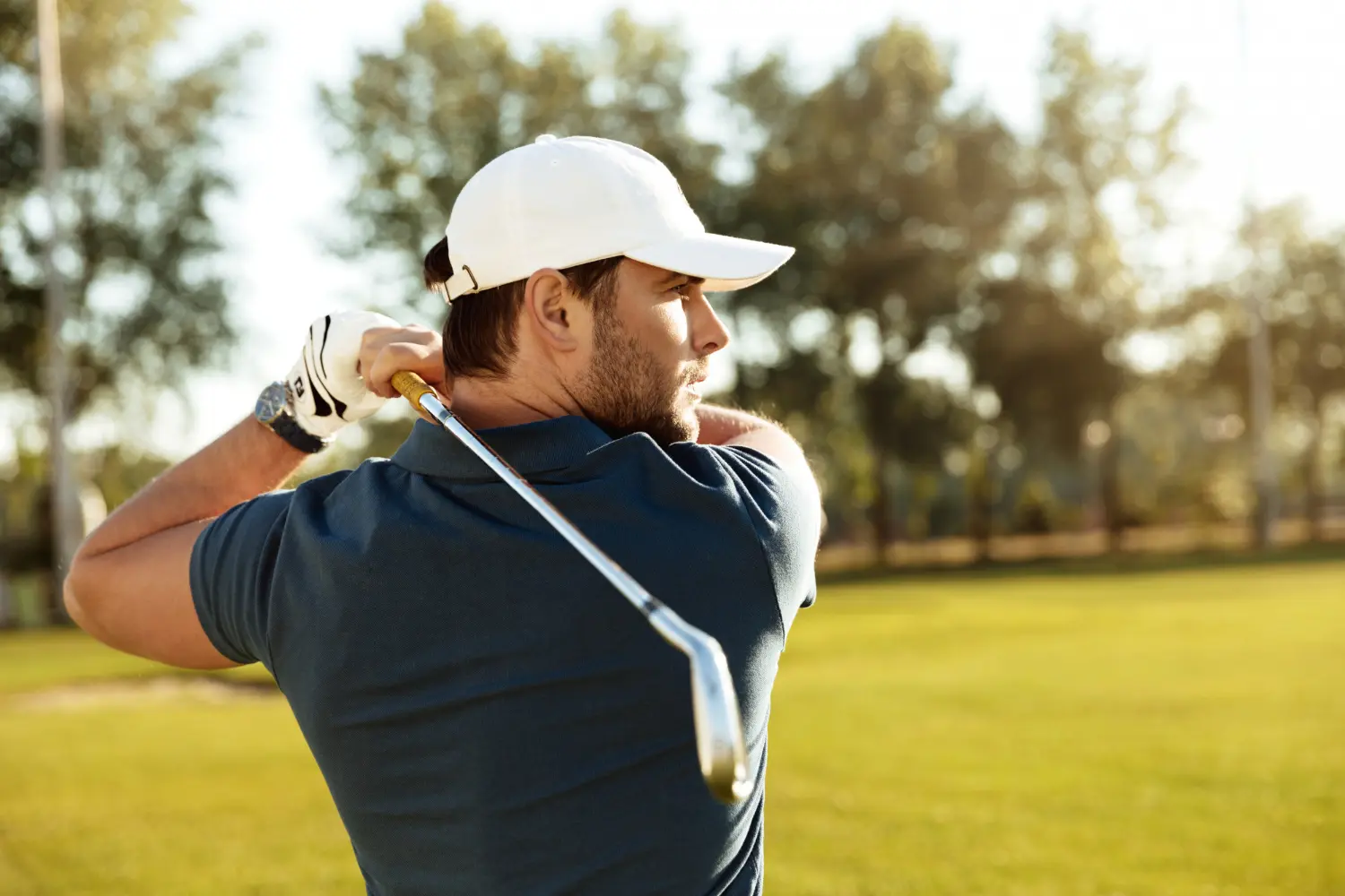Golfer completing a swing on a sunlit course