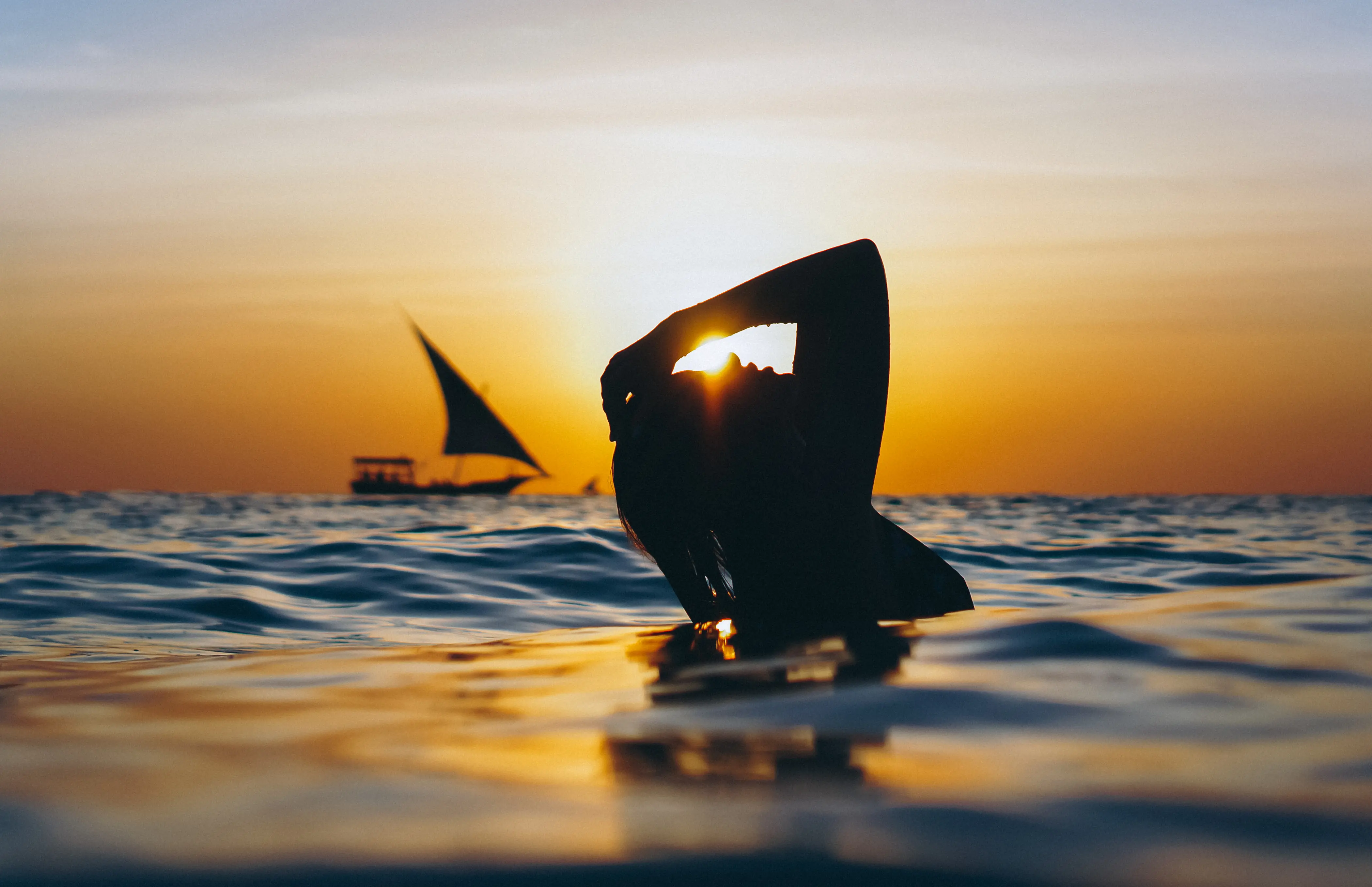 Water sports in the sea at sunset with a sailboat